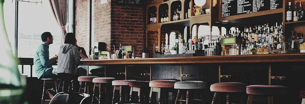 Zwei Kursteilnehmer sitzen an hölzerner Theke in einem Irish Pub